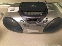Front view of silver and gray portable stereo with speakers, control buttons and display.