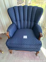 Front view of the blue wing back chair showing detailed upholstery and wooden armrests and legs.