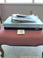 Front view of LG DVD and VHS combo showing front panel, remote, and manuals placed on top