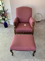 Front view of antique chair and ottoman set with pink salmon upholstery and carved wood details.
