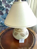Full view of table lamp showing ceramic base and large cream fabric shade.
