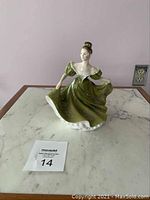 Front view of Royal Doulton Lynne figurine showing detailed face and flowing green dress on marble surface.