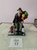 Front view of seated man holding balloons on reflective base