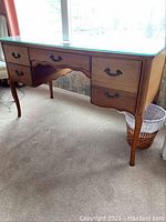 Front view of desk showing finish, glass top and drawer configuration