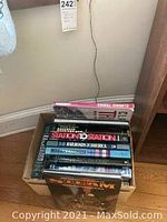 Photo showing multiple large books stacked vertically and horizontally in a box near a wall, titles include Station to Station, Railroads of North America, Modern Railways.