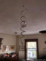 Spiral metal mobile with clear orb, hanging from ceiling in living room