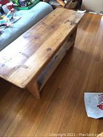 Angled side view showing wood grain, scratches, and lower shelf