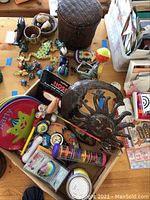 Image showing multiple plastic animal toys and figurines including ducks, penguins, turtle shapes, a woven basket, and various small toys and novelties on a wooden surface.