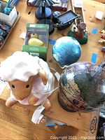 Lamb lamp next to two globes on a wooden surface, one small blue globe and one larger vintage-style globe.