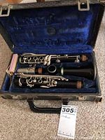 Vintage Vandoren clarinet disassembled in a blue velvet-lined carrying case, showing the instrument's black body and silver keys.