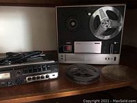 Sony reel-to-reel recorder, Marantz cassette recorder and four tape reels on wooden surface