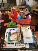 Box of assorted robot-themed items, children's toys, and figurines shown on table, including colorful plush toys, figurines, trays, and decorative accessories.