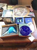 View of all items laid on table including glass bird, Swarovski moon and star in box, merlot coasters, glass dish and charger plate.