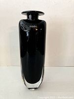 Front view of the signed Kosta Boda black glass vase on white background