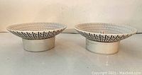 Pair of white geometric pattern ceramic candle holders from side showing shape and pattern.
