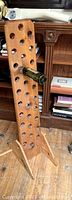 Solid wood wine rack viewed from side angle showing bottle holding holes and upright panel with two support legs.