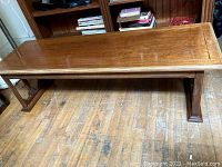 Full view of the vintage wood coffee table showing the rectangular top and carved legs.