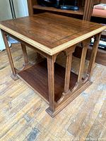 Angled side view showing table top, lower shelf, and decorative carved arches on side panels.
