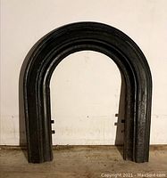 Front view of vintage black cast iron fireplace arch.