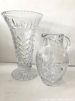 Front view of large crystal vase and crystal pitcher showing detailed cut patterns