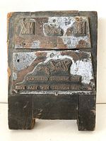 Front side of the printer block showing metal printing plates with reversed greeting text and decorative holiday motifs.