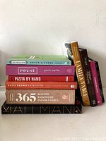 Cookbooks stacked showing spines with titles and authors, providing visual confirmation of lot contents