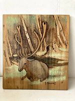 Front view of the wooden panel with the wood burning artwork of a deer in forest.