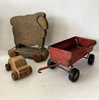 Photo showing the wooden sheep on wheels, wooden truck, and red metal ERTL toy wagon from the front angle