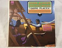 Front cover of the 'Goin Places' album showing Herb Alpert and a woman in a yellow biplane with colorful lettering.