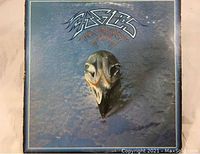Front cover of Eagles Greatest Hits 71-75 vinyl LP showing band logo, album title, and eagle skull graphic on blue background.