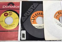 Close-up photo showing three vinyl singles with visible labels: Polydor 'Darling, I How Our Song' by Martha & The Vandellas, Arista Flashback Records 'People' by Dionne Warwick, and an additional Flashback Records single.