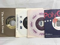 Front view of vinyl singles from Atlantic Group, Capitol, PolyGram labels with visible record center labels.