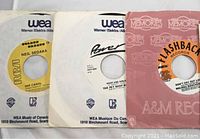 Photo showing 3 vinyl 45 singles in paper sleeves: Neil Sedaka on WEA, Pet Shop Boys on Power Records, and Melissa Manchester on Flashback Records.