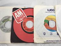 Close-up photo of three vinyl 45 rpm records on various labels A&M Records, WEA, and another partially visible