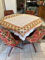 Photo showing the 4 floral fabric swivel chairs around the table covered partially with a floral patterned cloth.