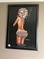 Framed print showing the full piece with a stylized image of a woman in a ruffled skirt, against a black background, signed by artist Angelina Wrona.
