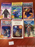 Front covers of six Choose Your Own Adventure paperback books laid out on a wooden surface.