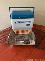 Rubbermaid Super Lunch Tote cooler with stainless steel veggie cooker/toaster and two metal racks on table.