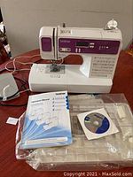 Sewing machine with foot pedal, power cord, instruction manual and software CD in plastic bag