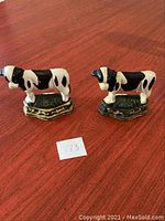 Pair of cast iron cow figurines showing both figures standing side by side on a wooden surface.