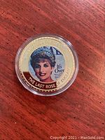 Gold plated coin encased in clear capsule showing front side with image of Princess Diana and engraved text.