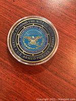 Photo of front side of the coin showing the U.S. Department of Defense emblem with eagle and surrounding text.