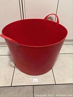Front view of large red plastic basket showing round shape and one handle visible.