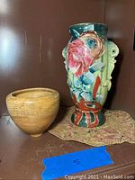 Large colorful Asian-style vase with floral decoration and smaller plain terracotta vase together on a surface.