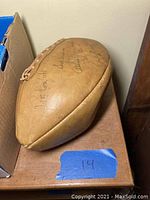 Photo showing side view of vintage Rawlings EA-2 classic leather football with visible signatures and weathered condition.
