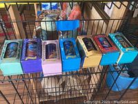 Six Disney Collector Series glass cups in original boxes displayed on metal shelf, showing colorful vintage packaging and designs.