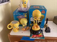 Four Tweety Bird items shown on a surface: a mug, two figurines, and a boxed water fountain in the rear.
