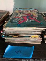 Stack of 49 comic books shown from side angle highlighting quantity and condition.