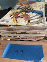 Stack of comic books with a blue paper marked number 57 in front.