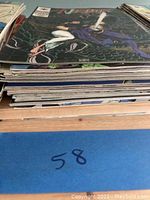 Side view showing a stack of approximately 10 comic books with visible spine wear and folded corners.